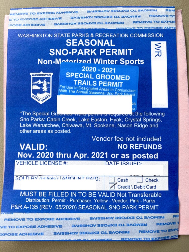 Close-up of a Sno-Park Permit displayed on a vehicle dashboard, required for parking at designated snow parks in Washington during winter recreation activities like sledding, snowshoeing, and skiing.