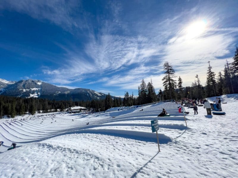 View from the top of the tubing hill at The Summit at Snoqualmie, looking down the snow-covered lanes as families and kids prepare to slide down in brightly colored tubes. The well-groomed hill features multiple lanes, a safe launch area, and a festive winter atmosphere—perfect for a day of family-friendly fun in the snow just an hour from Seattle.