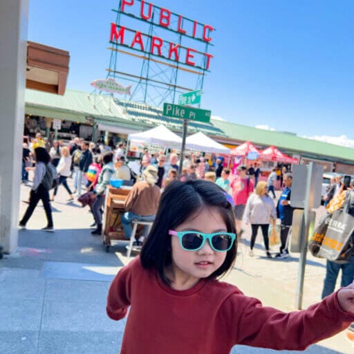 Toddler girl posing in front of the famous Public Market sign at Pike Place Market in Seattle, Washington.