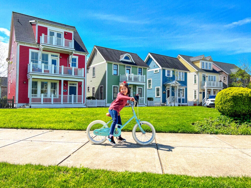 Seabrook Washington, charming coastal town in Washington, little toddler posing on her beach cruiser bike in front of colorful town houses.
