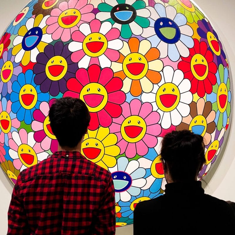 Teenager and mom admiring the colorful Murakami Flower Ball at the Seattle Asian Art Museum, a vibrant and iconic piece of contemporary Japanese art known for its cheerful floral faces and bold pop style.