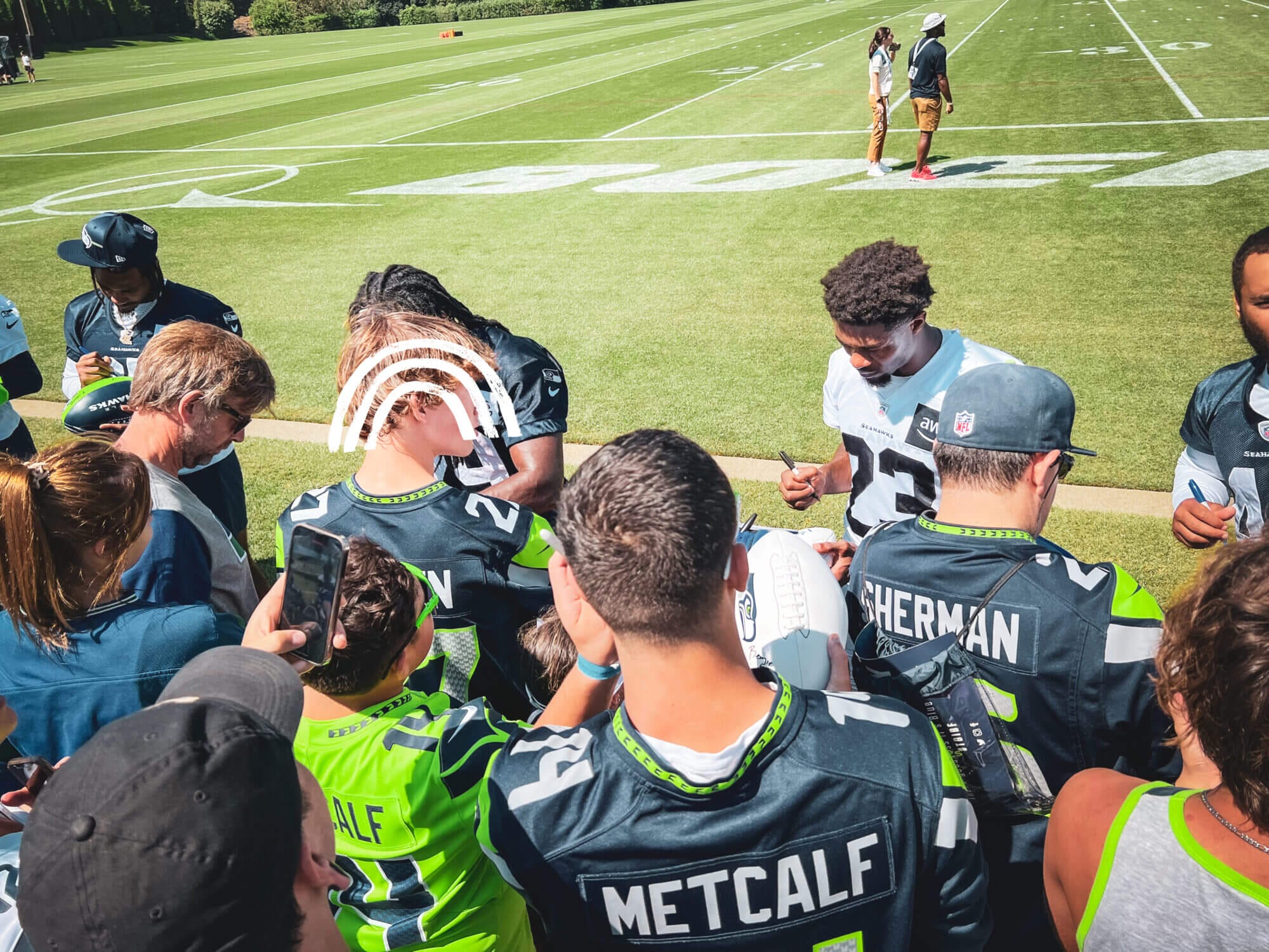 Seahawks fans in jerseys getting autographs at the side of the field during the summer Seahawks training camp.