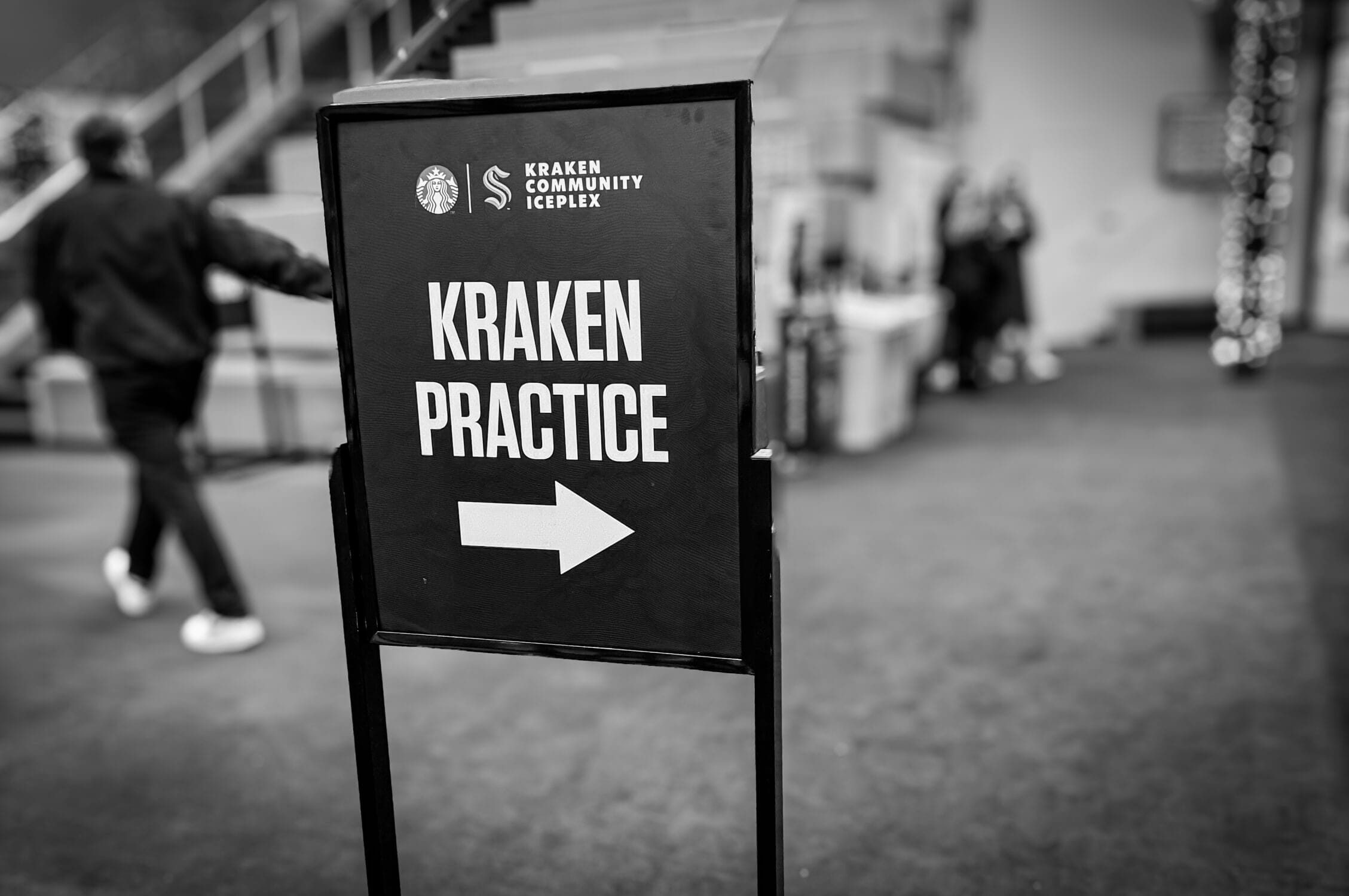 A Seattle Kraken practice sign with an arrow directs fans through the Kraken Community Iceplex, helping visitors easily navigate the facility. Whether attending a public practice session, exploring the ice rinks, or grabbing a meal at 32 Bar & Grill, this sign ensures that families and hockey enthusiasts can find their way to the action.