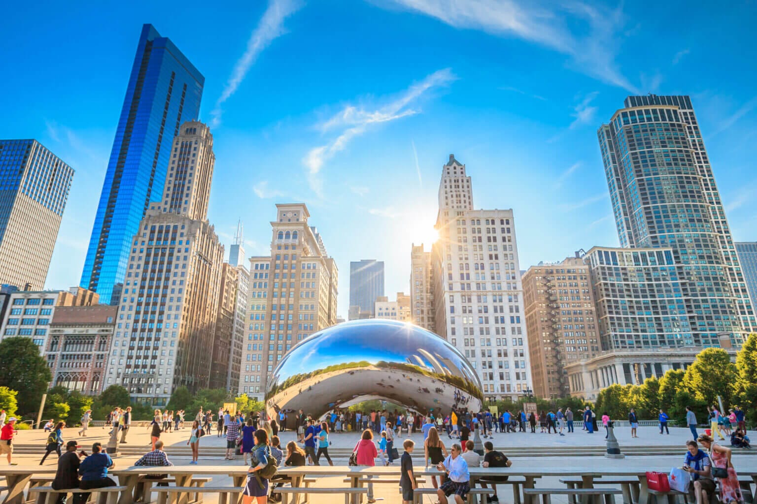 The iconic Chicago Bean sculpture, officially known as Cloud Gate, reflects the surrounding skyline of downtown Chicago, including nearby skyscrapers, under a bright sky. A popular stop for families visiting the city, this photo captures the sculpture’s polished, mirror-like surface and the lively atmosphere of Millennium Park.