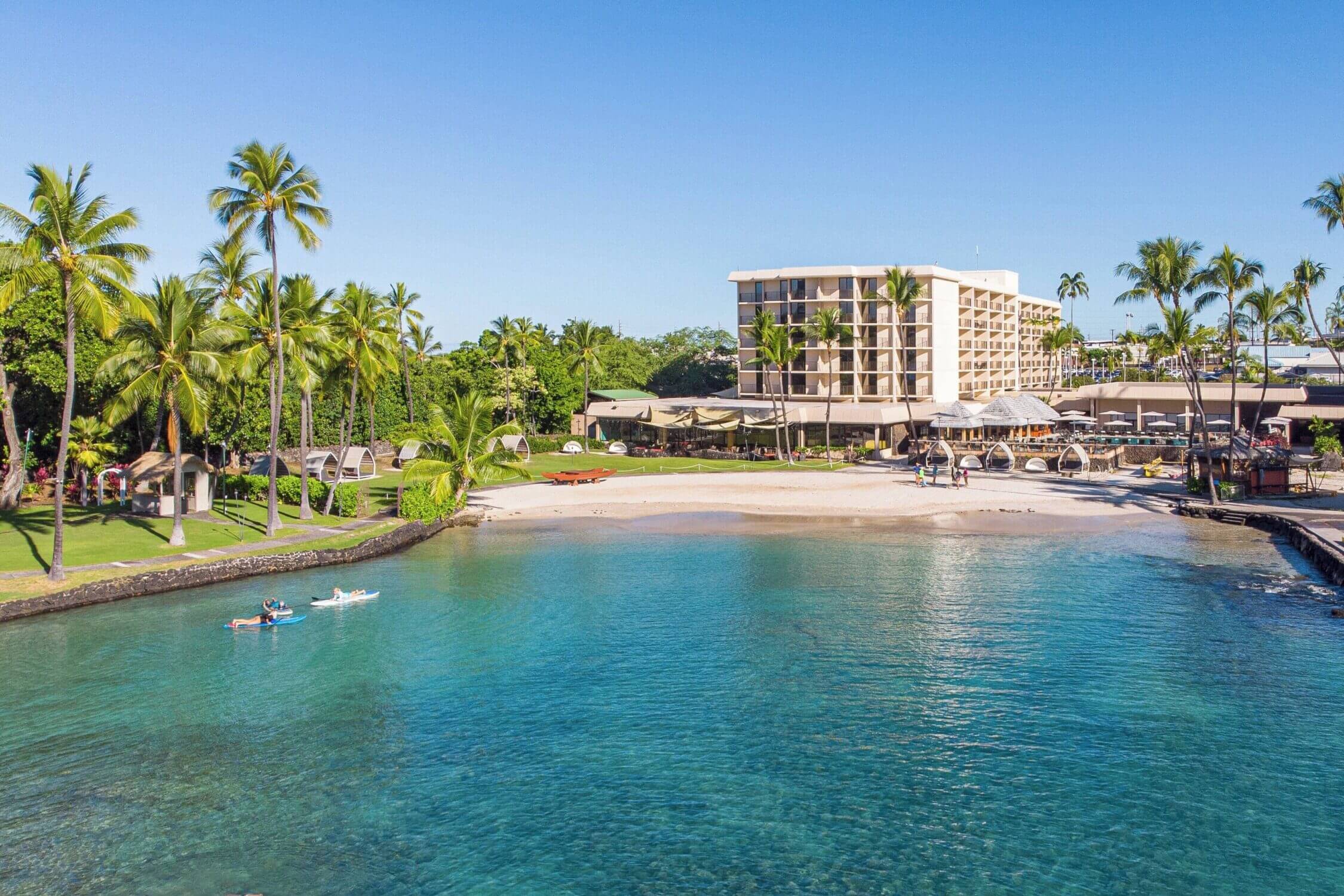 Mom and daughter learning how to paddle board in the calm, shallow waters just off the beach at the Courtyard by Marriott King Kamehameha’s Kona Beach Hotel on the Big Island. The protected bay makes it an ideal and safe spot for beginners and families with kids to try paddle boarding—one of the many ocean activities available right from this centrally located, family-friendly resort in Kailua-Kona.