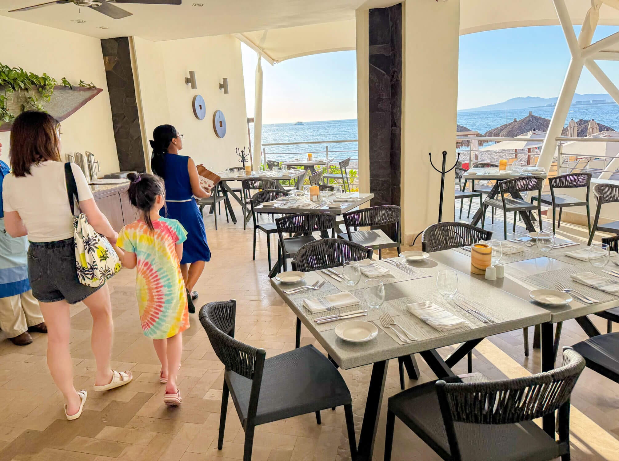 A mom and daughter walk hand-in-hand to their table at Castaways, the outdoor dinner restaurant at Dreams Vallarta Bay Resort, located just steps from the pool with stunning ocean views. Opening at 6 PM, it’s the perfect place for an early family dinner as the sun begins to set. With the all-inclusive dining option, guests can enjoy multiple entrées—ideal for sampling everything from grilled seafood to juicy steaks. The laid-back beachfront vibe and friendly service make Castaways a family favorite spot for winding down after a fun-filled day.