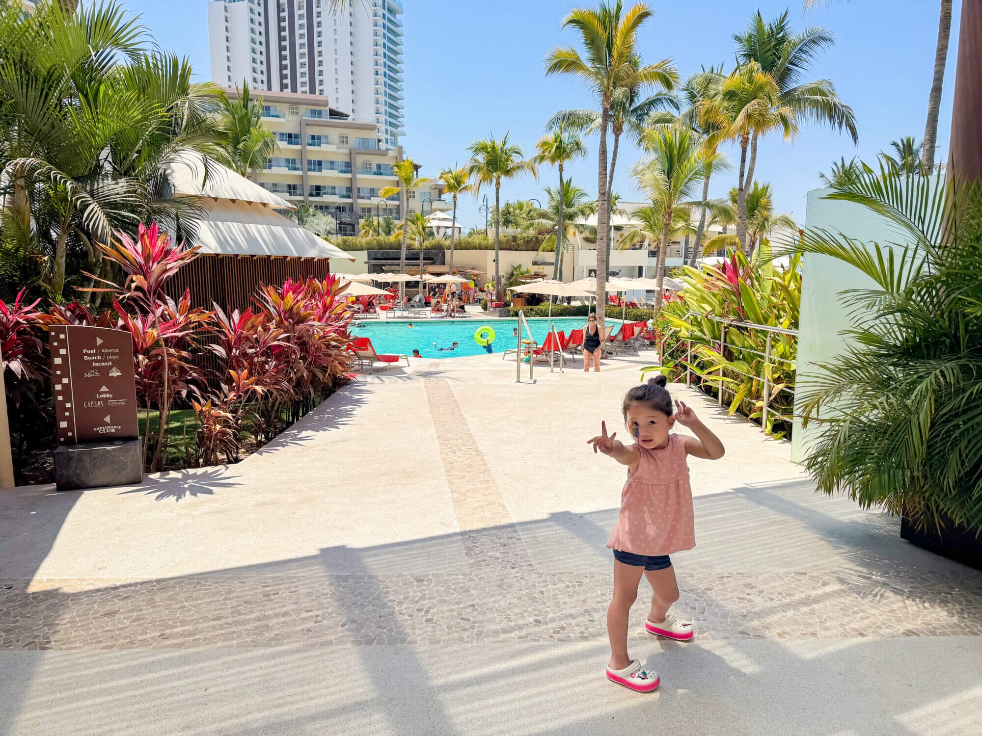 A toddler girl beams with excitement after being picked up from the Explorer’s Club at Dreams Vallarta Bay Resort, her face painted with colorful designs and ready for a fun-filled pool day. This all-inclusive, family-friendly resort in Puerto Vallarta offers the perfect mix of supervised kid activities and unforgettable family moments, from face painting to splashing in the resort’s multiple pools. With programs like the Explorer’s Club, parents can relax while kids enjoy creative fun and make new friends.