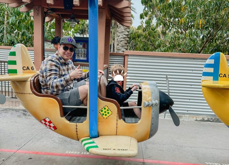 Dad and son enjoying the toddler-friendly Cargo Ace airplane ride at LEGOLAND California, a gentle spinning ride designed for young kids. With bright LEGO-themed planes and low height requirements, it’s one of the best attractions for preschoolers at the park, making LEGOLAND a top destination for families with little ones.