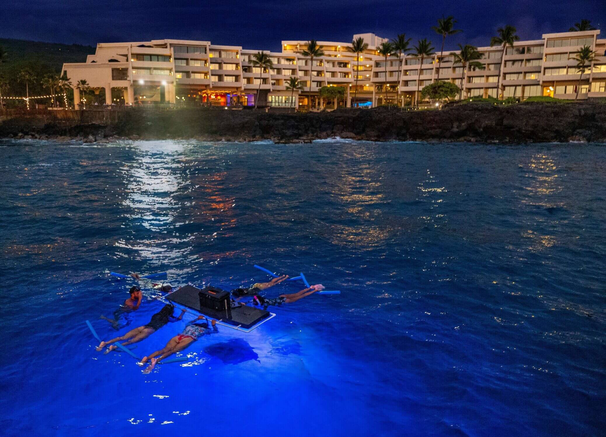 Nighttime manta ray tour at the Outrigger Kona Resort on the Big Island of Hawaii, with participants floating on a lit platform while watching a manta ray glide gracefully beneath the surface. Known as one of the best spots in the world for manta ray sightings, this experience offers families an unforgettable and safe opportunity to see these gentle giants up close—right off the resort’s shoreline.