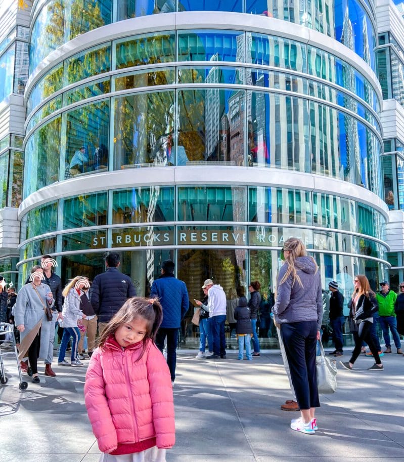 Young girl making a sad (funny) face while standing outside the Starbucks Reserve Roastery in Chicago, disappointed by the long line—highlighting this popular attraction on our list of things to do in Chicago with kids.