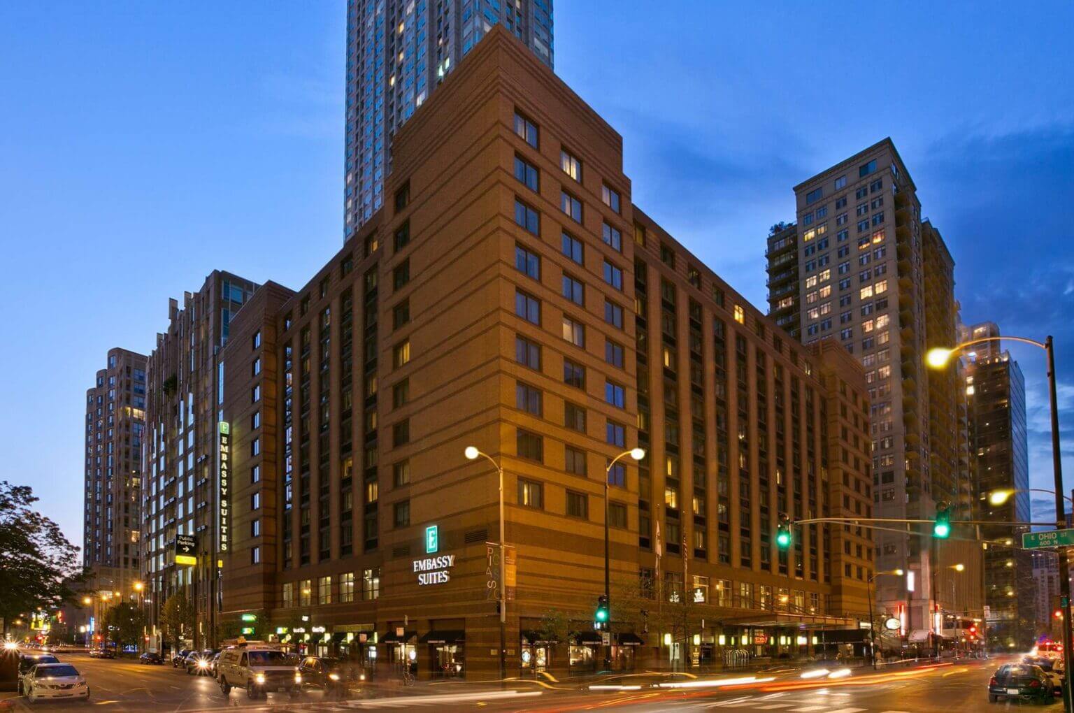 Exterior of Embassy Suites by Hilton Chicago at night, beautifully lit with warm lights reflecting off the modern glass facade. A welcoming sight for families returning after a day of exploring Chicago’s kid-friendly attractions in the River North neighborhood.