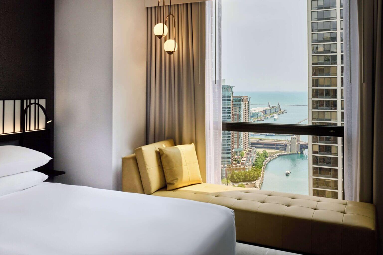 A hotel room at the Hyatt Regency Chicago with large windows offering a stunning view of the Chicago River and the bustling Riverwalk below. Located in the family-friendly Loop neighborhood, this hotel is one of the best places to stay with kids in Chicago due to its central location and beautiful riverfront views.