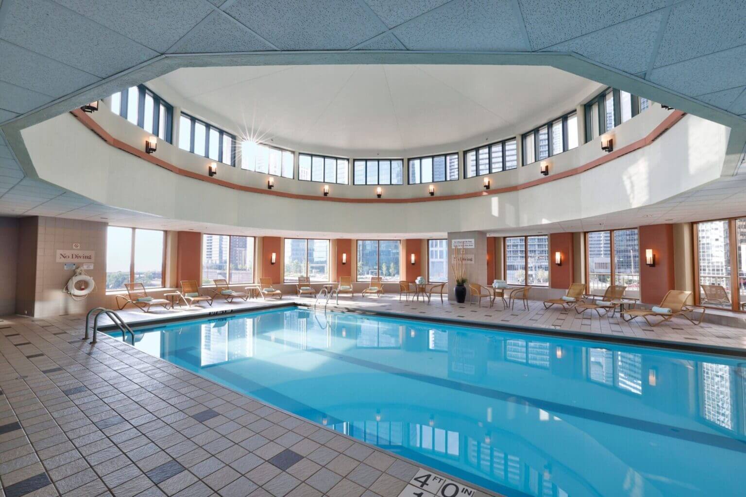 Indoor swimming pool at the Sheraton Grand Chicago, featuring lounge chairs and large windows that bring in natural light—perfect for families looking to unwind after a day of exploring the city.