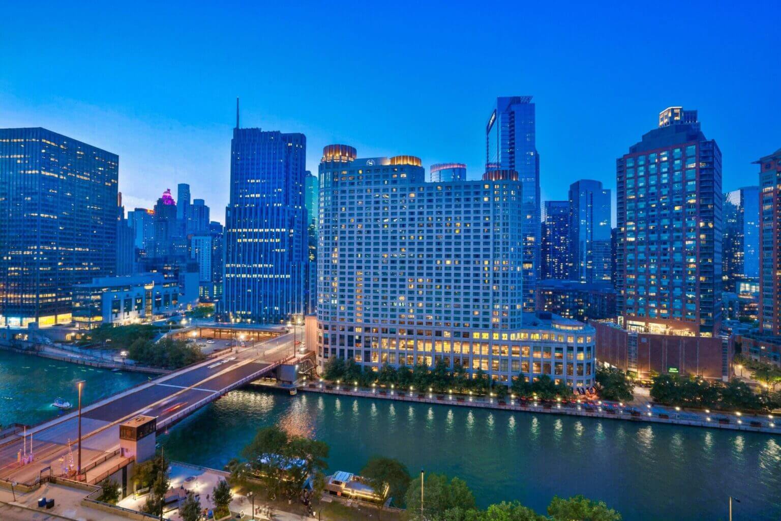 Nighttime view of the Sheraton Grand Chicago Riverwalk hotel, beautifully lit with reflections on the Chicago River—an excellent family-friendly hotel option located right on the riverfront and within walking distance to Millennium Park and Navy Pier.