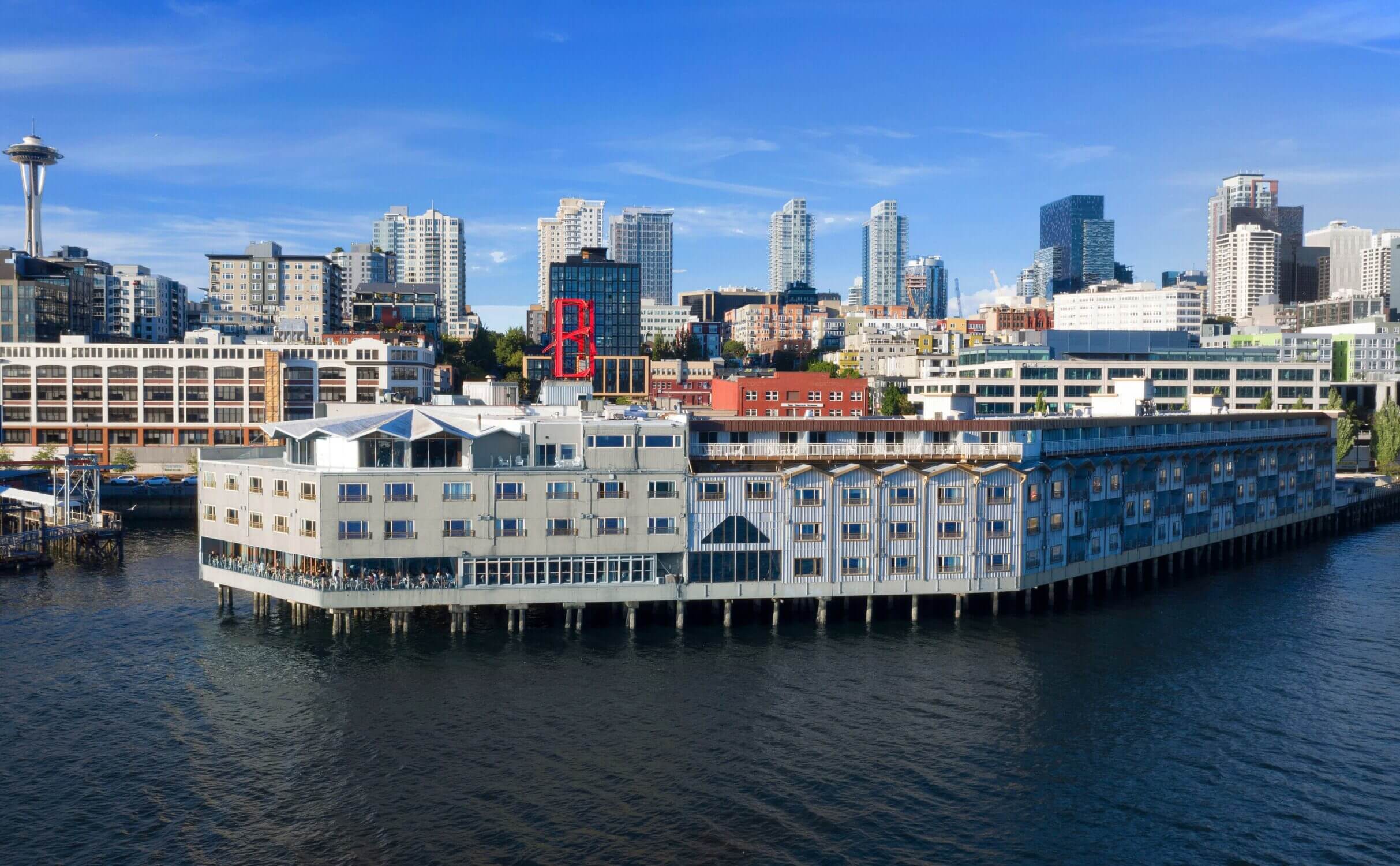 Aerial view of the Edgewater Hotel built over the water, with the Seattle skyline in the background—featured in our family travel blog on the best places to stay with kids in Seattle.