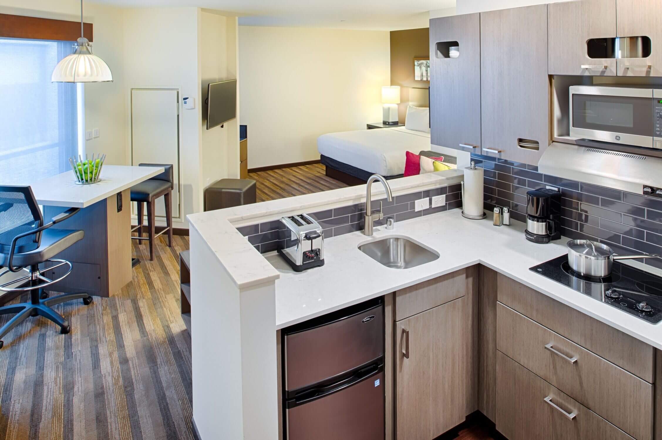 Kitchenette at Hyatt House Queen Anne in Seattle, featuring a full-size fridge, microwave, stovetop, sink, and plenty of counter space—ideal for families who prefer to prepare meals or snacks during their stay.