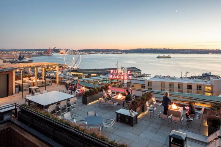 Rooftop balcony view from Inn at the Market, overlooking the iconic Pike Place Market neon sign, Seattle’s waterfront, and the Ferris wheel in the distance. A relaxing and scenic spot, perfect for families staying in downtown Seattle.