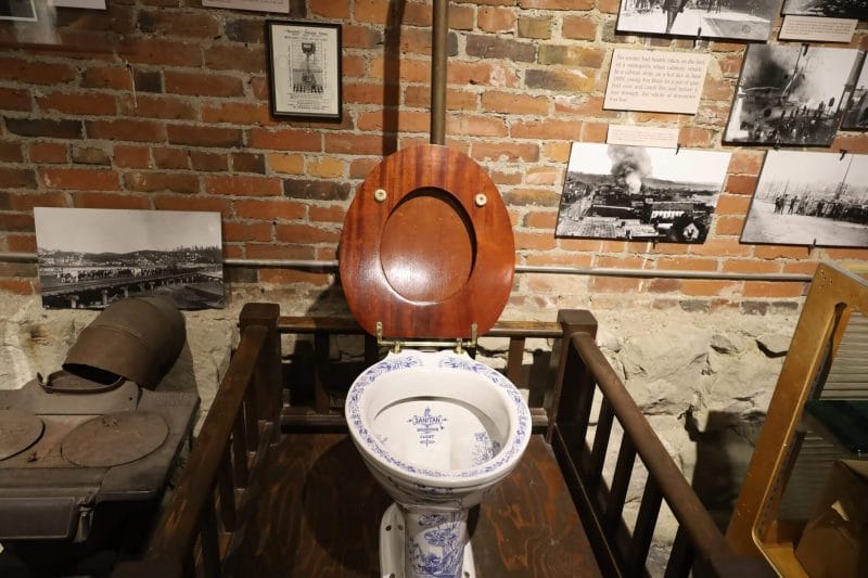 Seattle Underground Tour in Pioneer Square, a fun and educational thing to do with kids when visiting Seattle, featuring a historic toilet with blue floral designs and exhibits highlighting Seattle’s early history in the background.